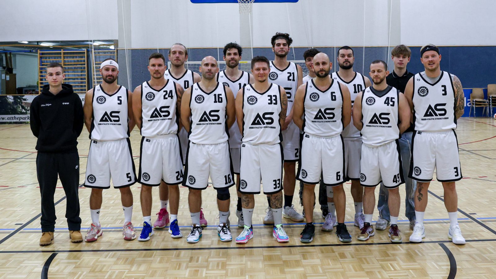 Die Herren-Landesligamannschaft der Baden Black Jacks in weißen Trikots beim Mannschaftsfoto in der Halle unter dem Basketballkorb