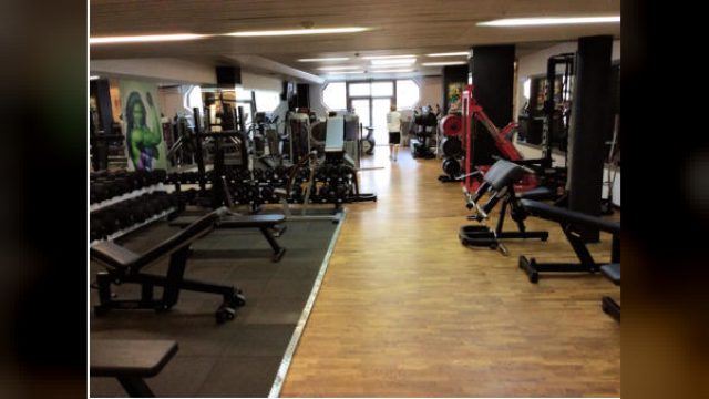 Trainingsfläche von BN4FIT in Baden mit Kurzhantelreihe, Hantelbänken und Kraftgeräten entlang eines Gangs mit Parkettboden