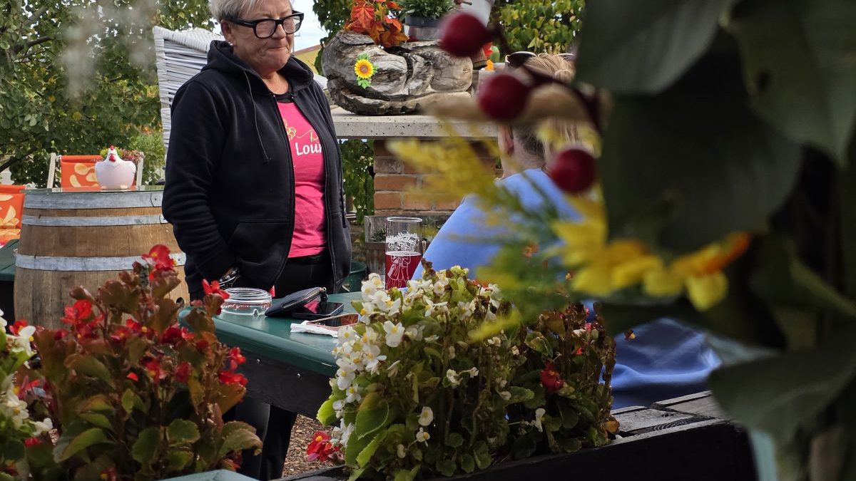 Der Gastgarten der Reb Lounge in den Weingärten von Pfaffstätten, im Vordergrund die Wirtin zwischen Blumenkästen