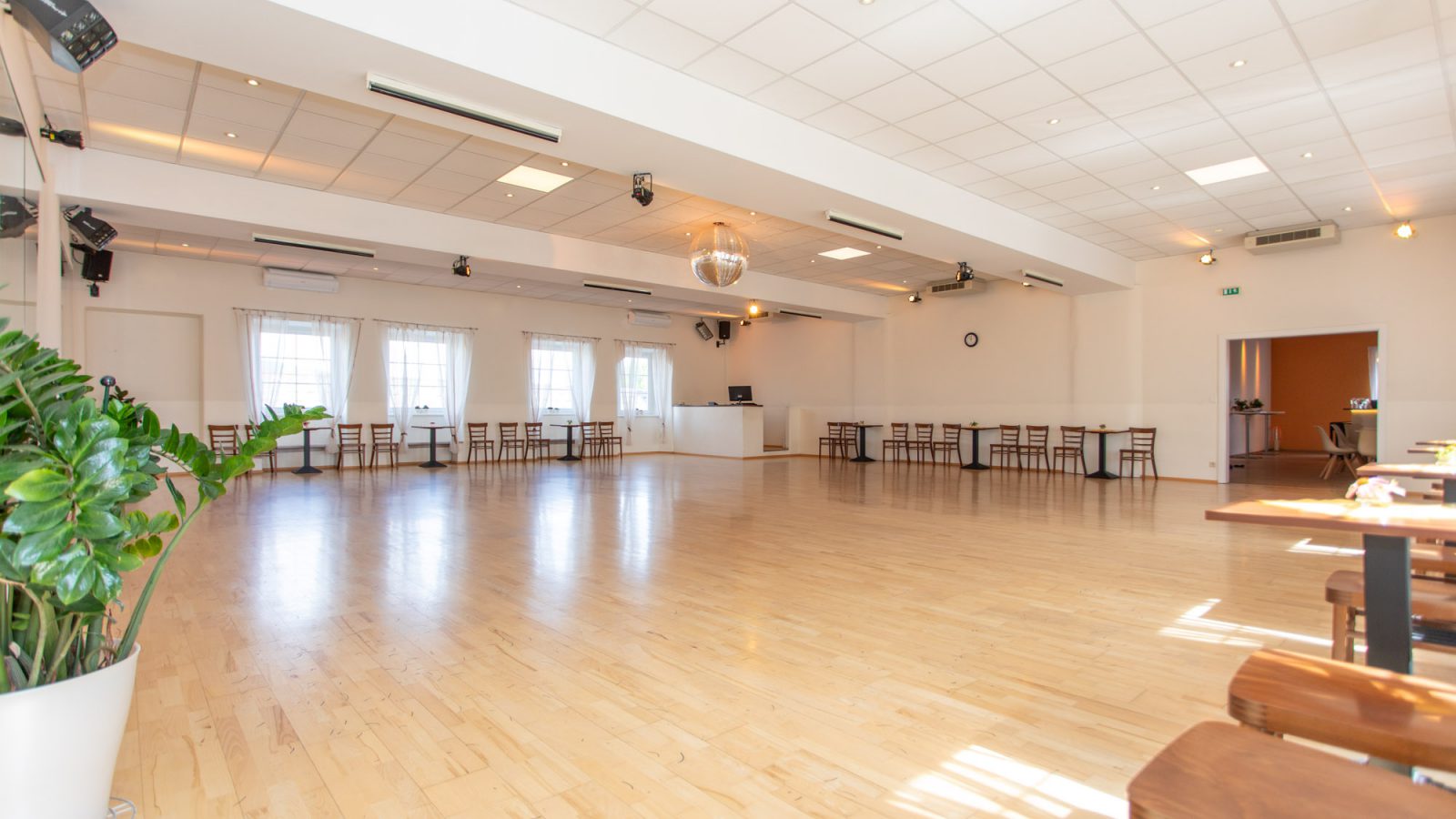 Großer Tanzsaal der Tanzschule Dobner in Bad Vöslau mit hellem Parkettboden, Spiegelkugel und Sitzplätzen an der Fensterfront