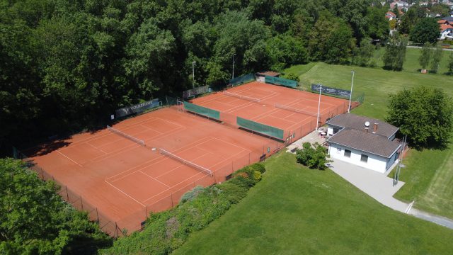 Luftbild der Tennisanlage des TC Pottendorf-Landegg mit vier Sandplätzen, Flutlichtmasten und weißem Clubhaus, umgeben von Wiese und Auwald