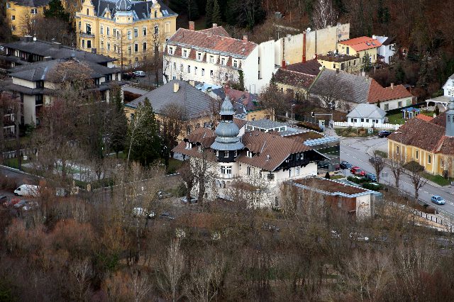 Blick von oben auf ein Hotelgebäude mit Türmchen und Erkern zwischen kahlen Bäumen, dahinter Villen und Straßen von Baden