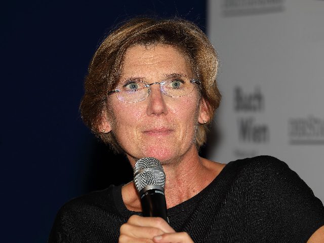 Beate Maly mit Brille spricht in ein Mikrofon, im Hintergrund der Schriftzug der Buch Wien