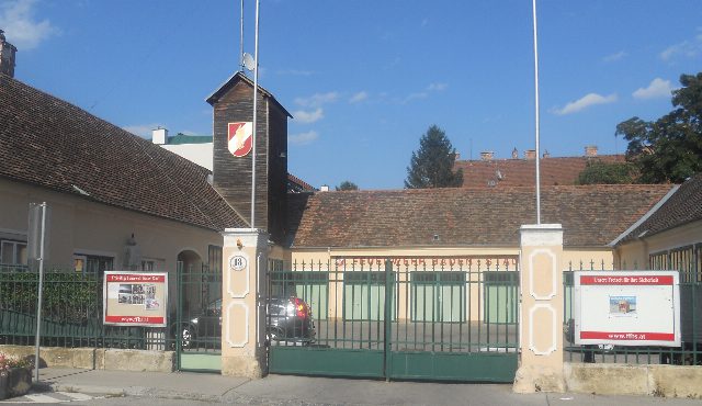 Feuerwehrhaus der Freiwilligen Feuerwehr Baden-Stadt in der Grabengasse mit grünem Tor, Holzturm mit Feuerwehrwappen und Infotafeln