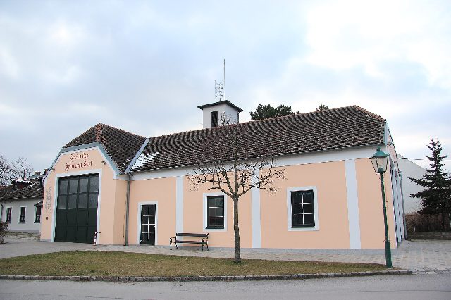 Feuerwehrhaus in Sooß: lachsfarbenes Gebäude mit grünem Tor, Schriftzug „Freiwillige Feuerwehr Sooß“ am Giebel und kleinem Turm auf dem Dach