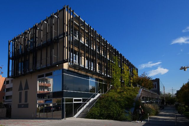 Campus Wieselburg der FH Wiener Neustadt, ein Bau mit Glasfront und dunklen Holzlamellen vor blauem Himmel