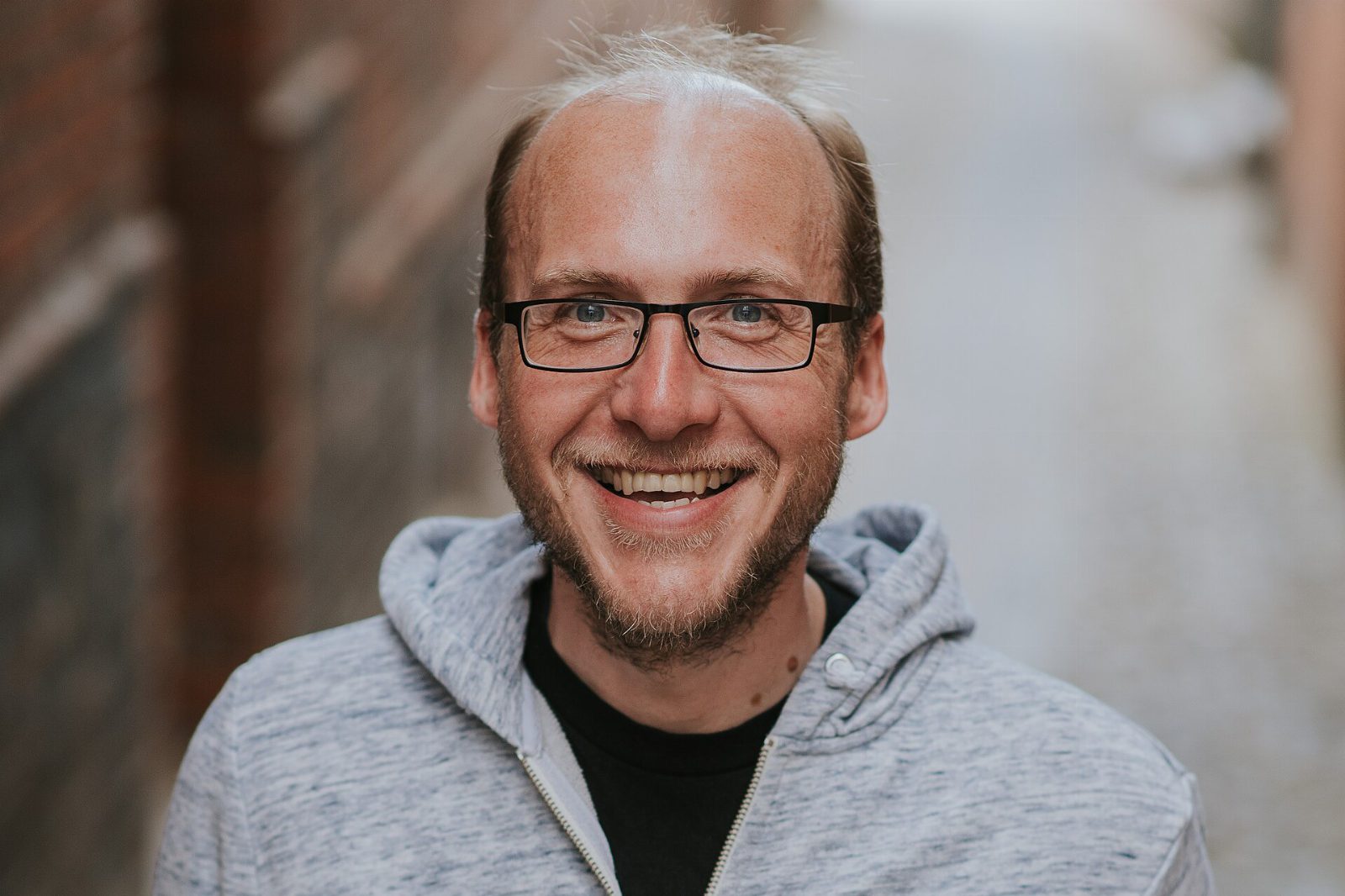Florian Freistetter mit Brille und grauer Kapuzenjacke lacht in die Kamera