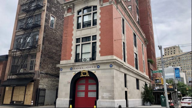 Die Feuerwache Hook & Ladder 8 in New York: ein schmales Backsteinhaus mit hellem Steinsockel, großem rotem Tor und der Aufschrift 8 Hook & Ladder 8 über dem Eingang