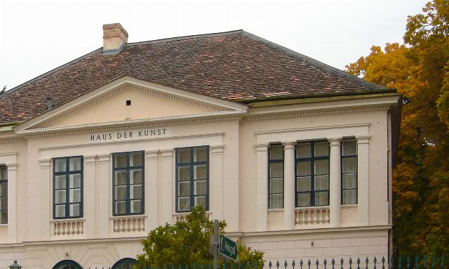 Fassade des Hauses der Kunst in Baden mit Giebel und Schriftzug, rechts herbstlich gefärbte Bäume