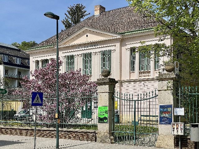 Haus der Kunst am Kaiser-Franz-Ring in Baden: hellrosa Villa mit Giebel und Schriftzug „Haus der Kunst“, davor ein Gittertor und eine blühende Magnolie