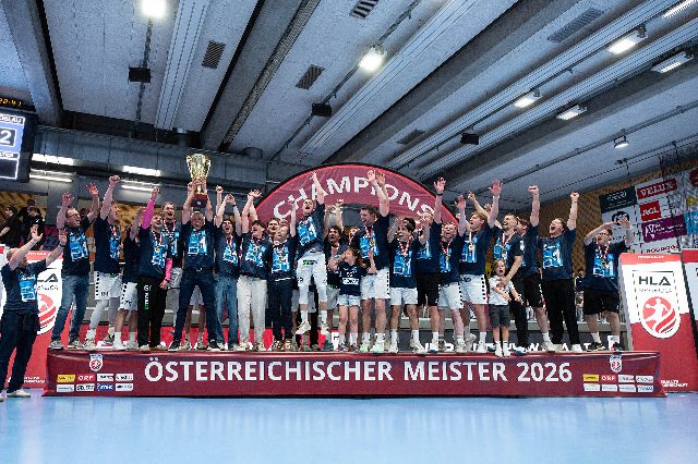 Handballer der Jags Vöslau jubeln mit Pokal auf einem Podest mit der Aufschrift Österreichischer Meister 2026
