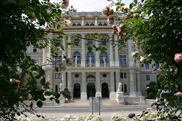 Justizpalast am Schmerlingplatz in Wien, Sitz des Obersten Gerichtshofs: Säulenfassade mit Freitreppe und zwei Löwenfiguren, im Vordergrund Rosenzweige