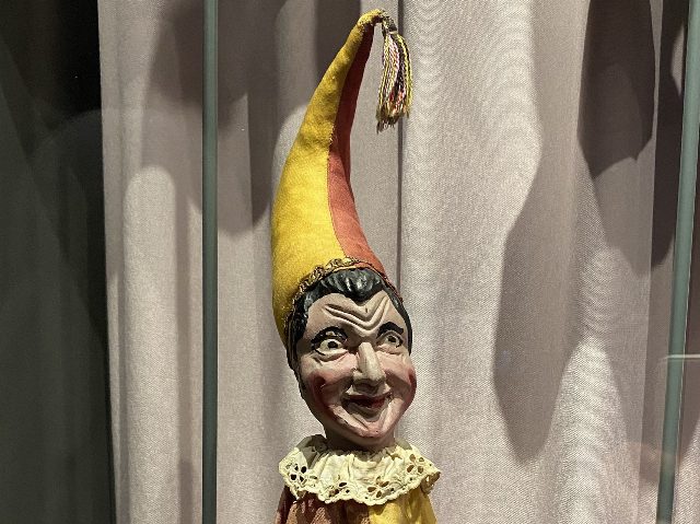 Alte Kasperl-Handpuppe aus dem Wiener Prater mit geschnitztem Holzkopf, breitem Grinsen und gelb-roter Zipfelmütze