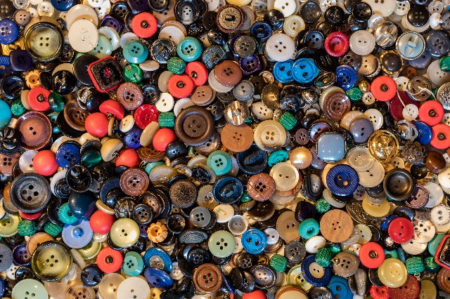 Viele bunte Knöpfe aus Holz, Metall und Kunststoff, dicht nebeneinander von oben fotografiert