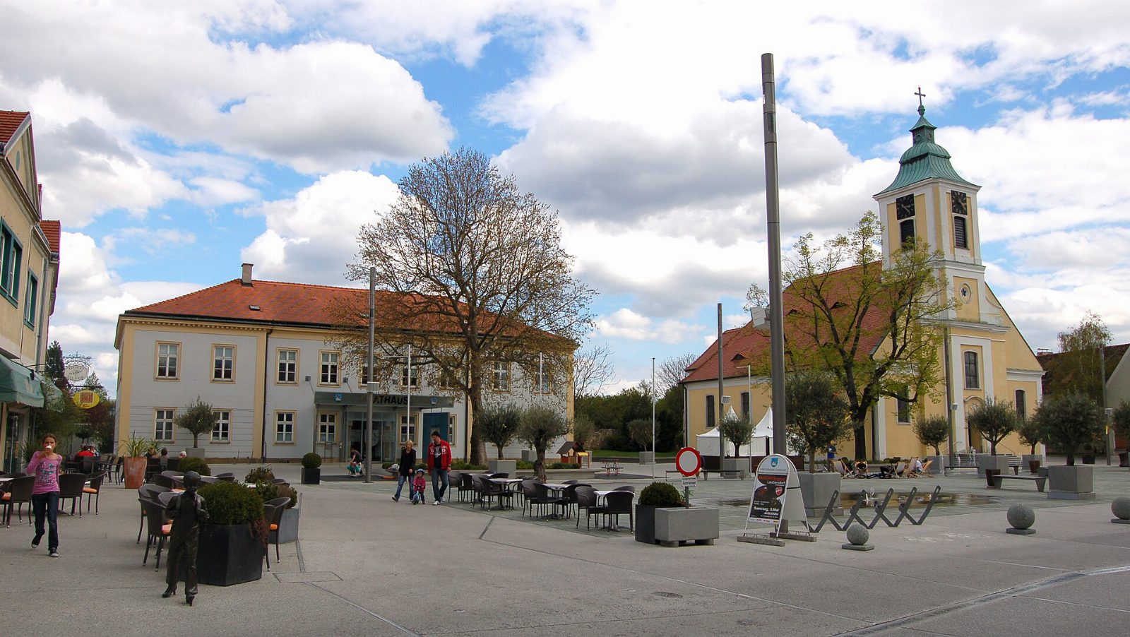 Kirchenplatz in Leobersdorf mit dem Rathaus links und der gelben Pfarrkirche zum heiligen Martin mit grünem Turmdach rechts