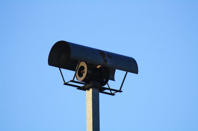 Motorsirene mit gewölbtem Regendach auf einem Mast vor blauem Himmel, aufgenommen in Gaaden bei Mödling