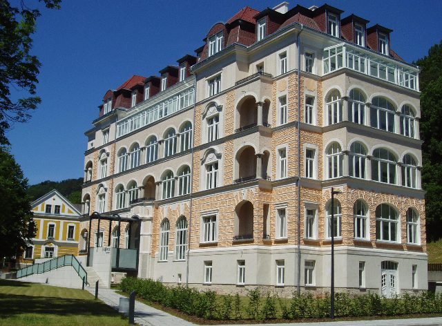 Das renovierte Curhotel d’Orange in Neuhaus, ein vierstöckiger Bau mit Erkern, Rundbogenfenstern und rotem Dach vor blauem Himmel