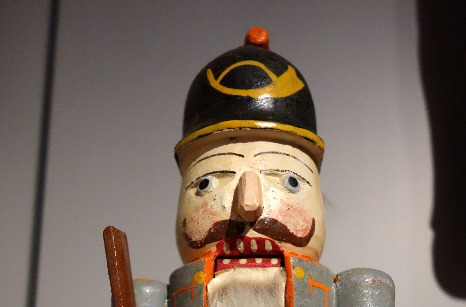 Kopf eines alten bemalten Nussknackers aus Holz mit schwarzem Helm, Schnurrbart und Fellbart