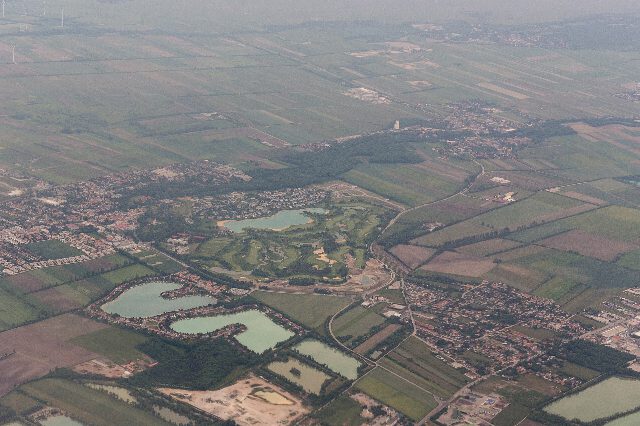 Luftbild von Oberwaltersdorf mit Siedlungen, einem Golfplatz und mehreren türkisen Teichen zwischen Feldern