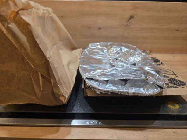 Die Verpackung der Lieferung: Pizzakarton und Schalen auf dem Tisch.
