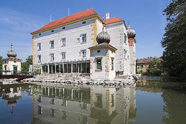 Wasserschloss Kottingbrunn mit Zwiebeltürmen, das sich im Schlossteich spiegelt
