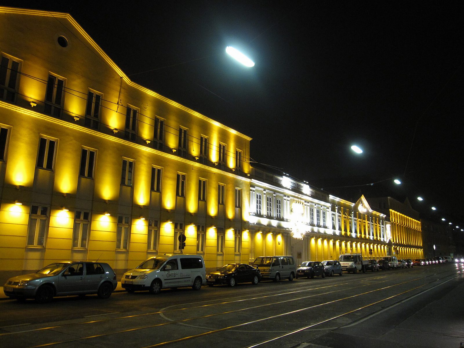 Beleuchtete gelbe Fassade der Schlumberger-Kellerei in der Heiligenstädter Straße in Wien bei Nacht, davor parkende Autos