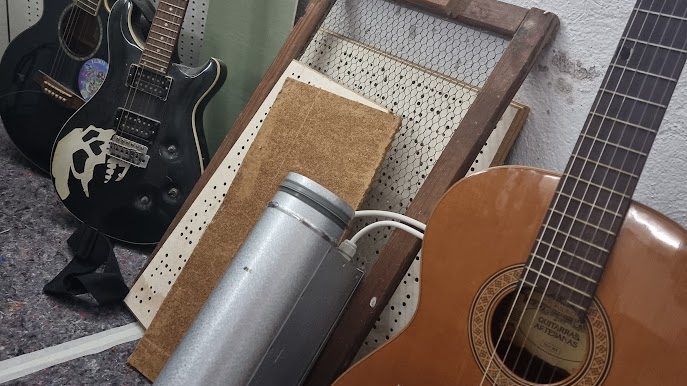 Zwei E-Gitarren und eine Konzertgitarre an einer Wand gelehnt