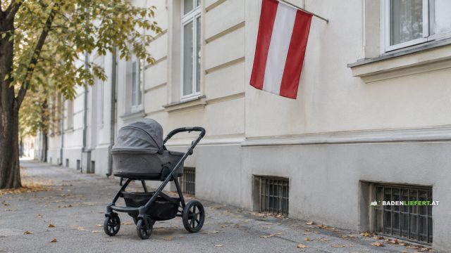 Leerer Kinderwagen auf einem Gehsteig mit Herbstlaub vor einer hellen Hausfassade, an der eine rot-weiß-rote Fahne hängt