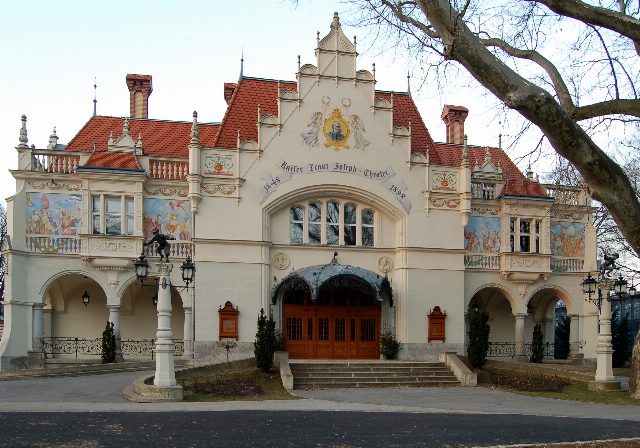 Fassade des Stadttheaters Berndorf mit Wandmalereien, Kaiserbild im Giebel und Holztor
