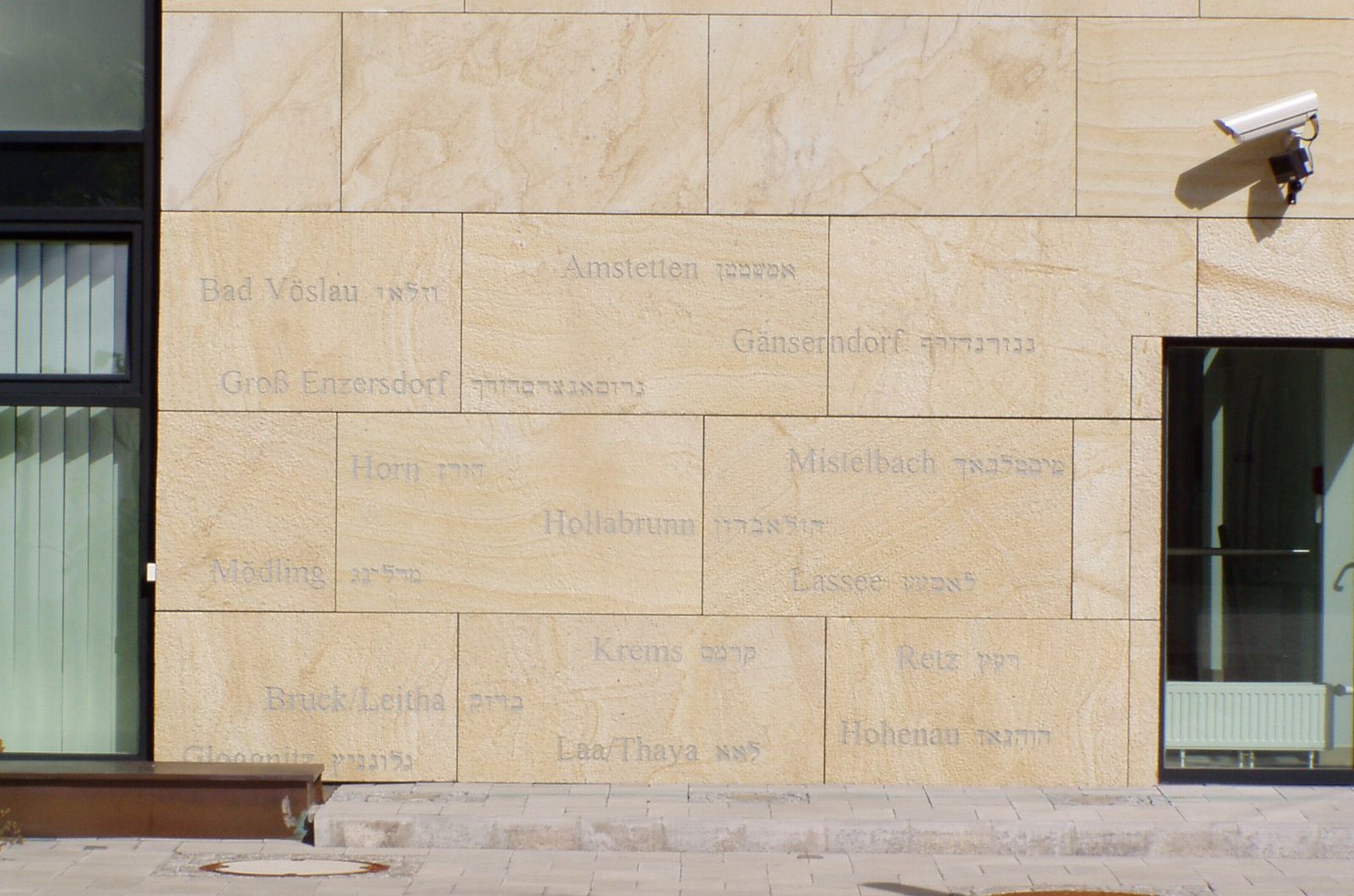 Sandsteinwand mit eingravierten niederösterreichischen Ortsnamen in lateinischer und hebräischer Schrift