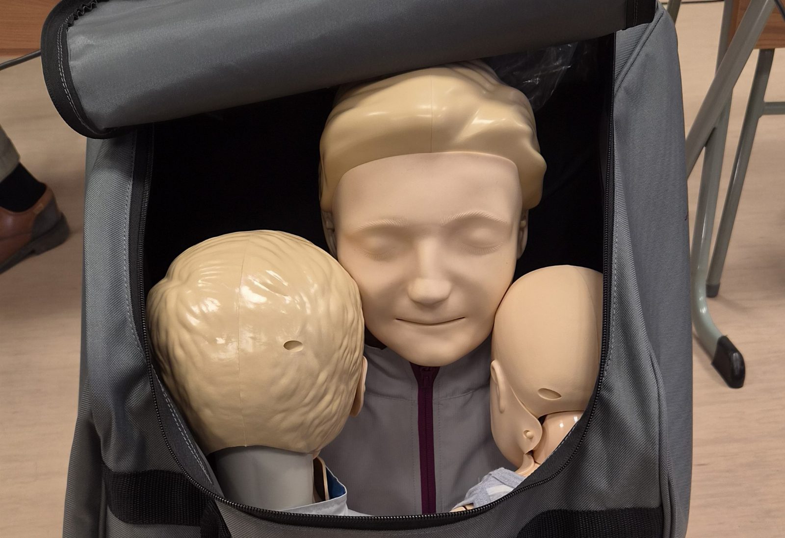 Drei Übungspuppen für Wiederbelebung in einer grauen Tasche: ein Erwachsener, ein Kind und ein Säugling