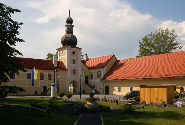Innenhof des Wirtschaftshofs von Schloss Kottingbrunn mit Uhrturm, Zwiebelhaube und Rasenfläche