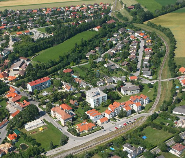 Luftbild von Wöllersdorf-Steinabrückl mit Wohnhäusern und Bahnstrecke. Ortsansicht, nicht die Tankstelle