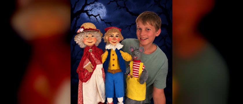 Ein Bub mit drei Handpuppen, einer Großmutter mit Strohhut, dem Kasperl und einer Maus in Latzhose, vor nächtlichem Himmel mit Vollmond