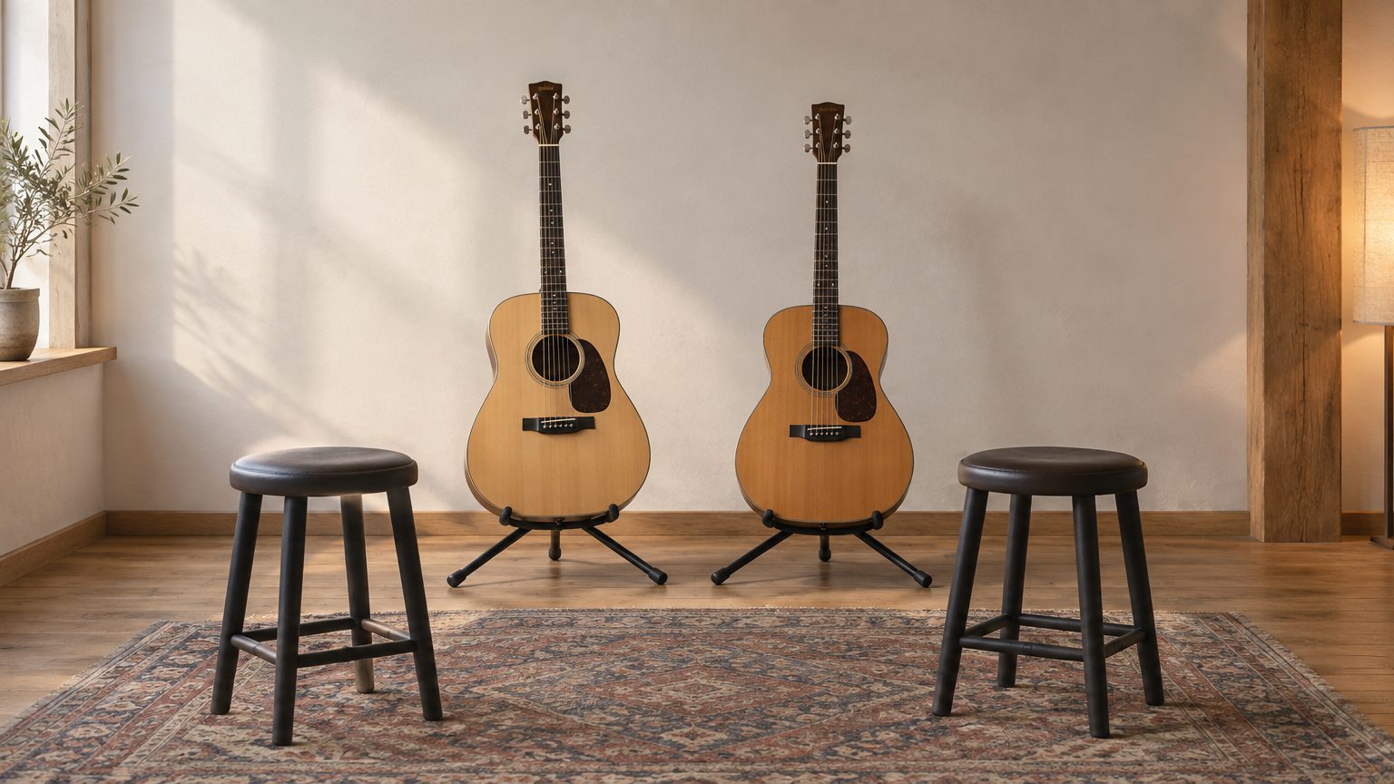 Symbolbild: zwei Akustikgitarren auf Ständern vor einer hellen Wand, daneben zwei Hocker