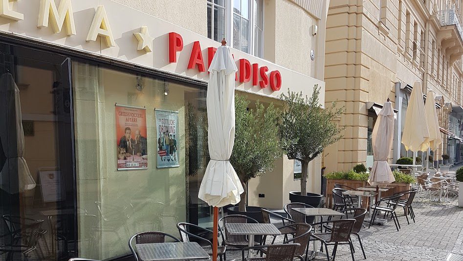 Eingang des Cinema Paradiso Baden mit roter Leuchtschrift und Schanigarten - Veranstaltungsort, kein Bild der Veranstaltung